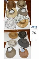 Overview of hats lot on table, showing 12 hats including wide brim sun hats and visors in straw and fabric.