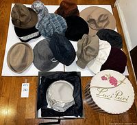 Overview of 15 hats laid out on floor including various styles, colors, and the Luci Puci hat box.