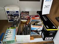 Image showing various boxed light bulbs including compact fluorescent, halogen Sylvania, floodlight, and SuperBright, plus The Original Drain Blaster in box