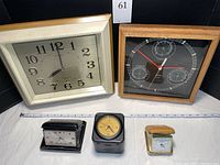Grouped view showing the Seiko wall clock, Sunbeam weather center, Sony radio alarm, Dunhill and Seth Thomas travel clocks on a white surface with measuring tape