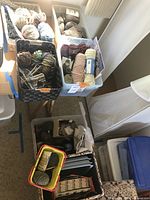 Multiple baskets and bins filled with skeins of yarn in natural and dyed colors, knitting needles, and other knitting supplies