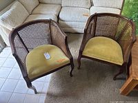 Pair of rattan barrel-back chairs with yellow-green velvet seats, viewed from the top and side showing the curved wooden frame and rattan backs with wear.