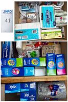 Top-down view showing paper napkins labeled Kirkland, a large pack of paper towels, packs of plates, and some small boxed items including mini silverware.