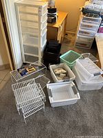 Overall group shot showing a variety of plastic bins in different colors and sizes, wire stackable shelves, and one tall plastic drawer organizer unit.