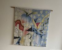 Silk wall hanging with light blue background and whimsical floral and abstract shapes hung on wall with wood dowel