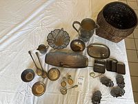 Full lot overview showing all silver plated serving items, sterling silver pieces, and dark wicker basket.