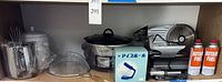 Wide shot showing multiple kitchen items including food slicer, Crock-Pot, torch, and cans of fuel