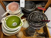 Stacked plastic and metal strainers with some matching bowls, various sizes and designs