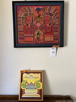 Photo showing both framed artworks on wall and standing on surface: textile art with elaborate design on top, original painting below