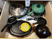 Drawer open shot showing all cookware items together including pots, skillets, platter, and utensils
