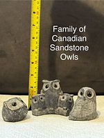 Photo showing five Canadian sandstone owl figurines in varying sizes next to measuring tape for scale, highlighting intricate carving details and overall condition.