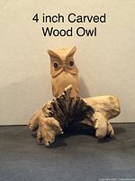 Front view of a 4 inch hand carved wooden owl on driftwood with distinctive eye and feather details.