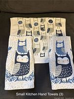 Three kitchen hand towels with large owl prints in blue and beige shades