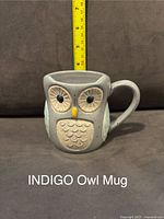Front view of an indigo ceramic mug shaped like an owl with textured wings and large eyes, about 3.5 inches tall.