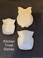 Photo showing three white ceramic owl-shaped kitchen trivet dishes with embossed detailing and distinct owl patterns.
