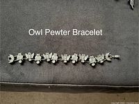 Pewter owl bracelet laid flat to show linked owl design and clasp