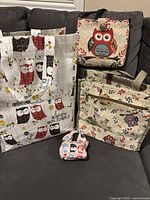 Photo of two owl purses and two owl shopping bags on a dark couch, showing fabric patterns and general size.
