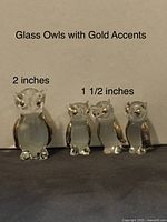 Photo of two glass owl figurines against a white background with text noting their sizes and gold accents