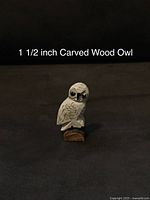 Front view of the carved wooden owl showing detailed feather and eye carving, sitting on a wooden base.