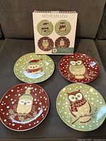 Four owl plates arranged in front of the packaging box showing the collectible set