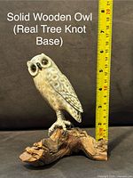 Solid carved wooden owl perched on real tree knot base with measuring tape showing height approx. 7 inches.