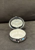 Open view of pill container showing tri-section interior compartments and hinged lid