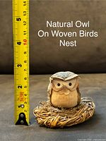 Close-up of natural owl figurine on woven bird's nest next to a tape measure showing height as approximately 2.5 inches.