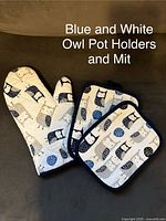 Blue and white owl pot holders and oven mitt laid out showing owl print and overall condition.