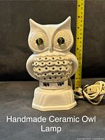Front view of one white handmade ceramic owl lamp with textured design, colorful large eyes, and electrical cord, shown with measuring tape indicating height approximately 8 inches.