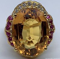 Close-up front view of the ring showing the large oval golden honey citrine gemstone surrounded by small rubies and diamonds or sapphires, set in 24K gold plated sterling silver band.