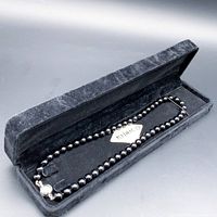 Black onyx beaded necklace displayed inside a black velvet jewelry box, showing full length and silver box clasp.