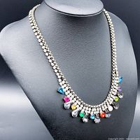 Front view of multi-colored rhinestone necklace on display bust showing colorful teardrop and round rhinestones along silver-tone chain.