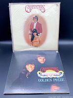 Photo of two vinyl record albums by The Carpenters, white cover portrait album on top and black Golden Prize album below.