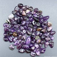Overview of multiple polished natural amethyst loose stones spread out showing color variation and size differences.