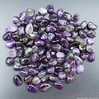 Top view of the collection of natural amethyst loose stones spread out on a flat surface showing variety in size and color.