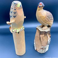 Two hand-carved wooden bird sculptures from Japan, an owl and a Rock Ptarmigan, both signed, displayed against a black background.