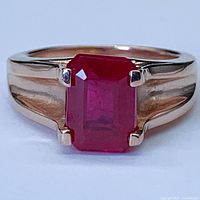 Front view of the ring showing the baguette-cut red ruby centerpiece and rose gold plated band.
