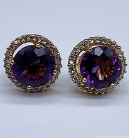 Front-on view of both earrings showing purple sapphire center and white sapphire halo