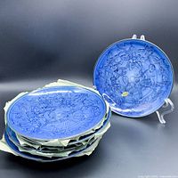 Group of five blue porcelain plates stacked with intricate raised floral design visible on top plate