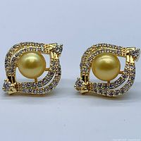 Front view of both golden pearl earrings showing pearl and cubic zirconia settings