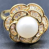 Close-up front view of gold-plated ring with pearl and crystal floral design.