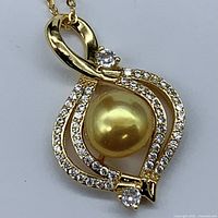 Close-up front view of the golden pearl pendant showing the cultured pearl and surrounding bezel with cubic zirconia stones