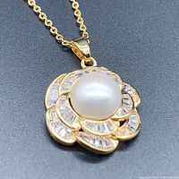 Close-up front view of flower-shaped pendant showing central pearl and surrounding crystals