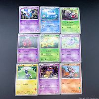 Top view showing all nine Japanese Pokemon cards in protective sleeves arranged in three rows of three on a dark grey surface.