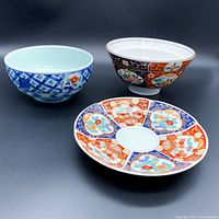 Image of three Arita Imari porcelain items including two bowls and a saucer plate, showing designs and colors.