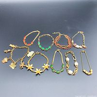 Overview of the 10 bracelets showing variety of designs including floral motifs, charm, bead and chain styles with gold-tone and colored accents.