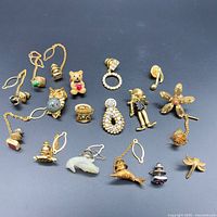 Collection of assorted lapel and pin brooches displayed on black background showing various designs including animal, floral, and decorative shapes.