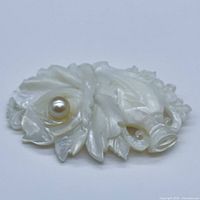 Close-up image of the hand-carved floral brooch showing the detailed petals and the centered genuine pearl accent.