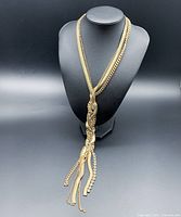Full necklace displayed on black jewelry bust, showing braided design and tassel ends.