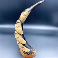 Front view of hand-carved four owl stack sculpture showing details of owl faces and feather textures with natural material base.